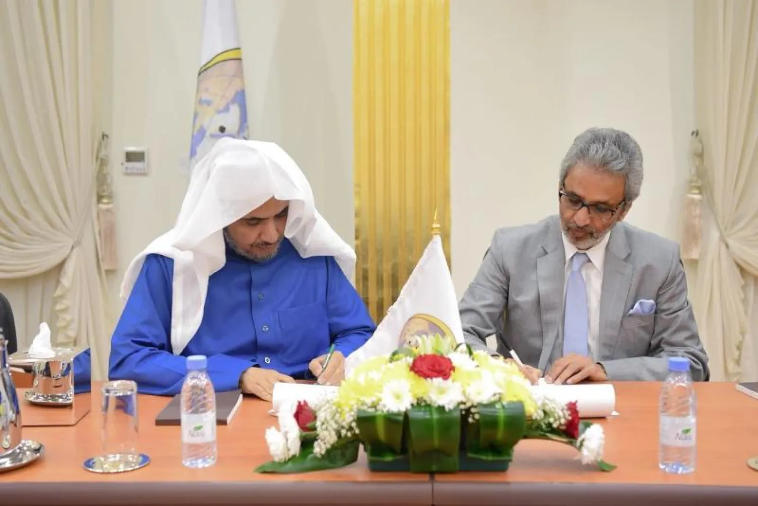 الدكتور محمد العيسى والدكتور باوا جين خلال توقيع الاتفاقية («الشرق الأوسط»)