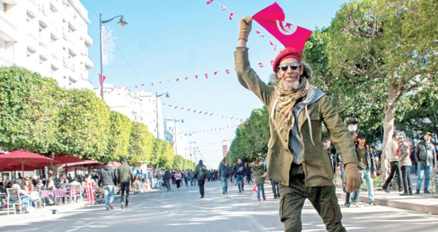 تونسي يلوح بعلم بلاده خلال مسيرة بذكرى 7 سنوات على الثورة التونسية (أ.ب)