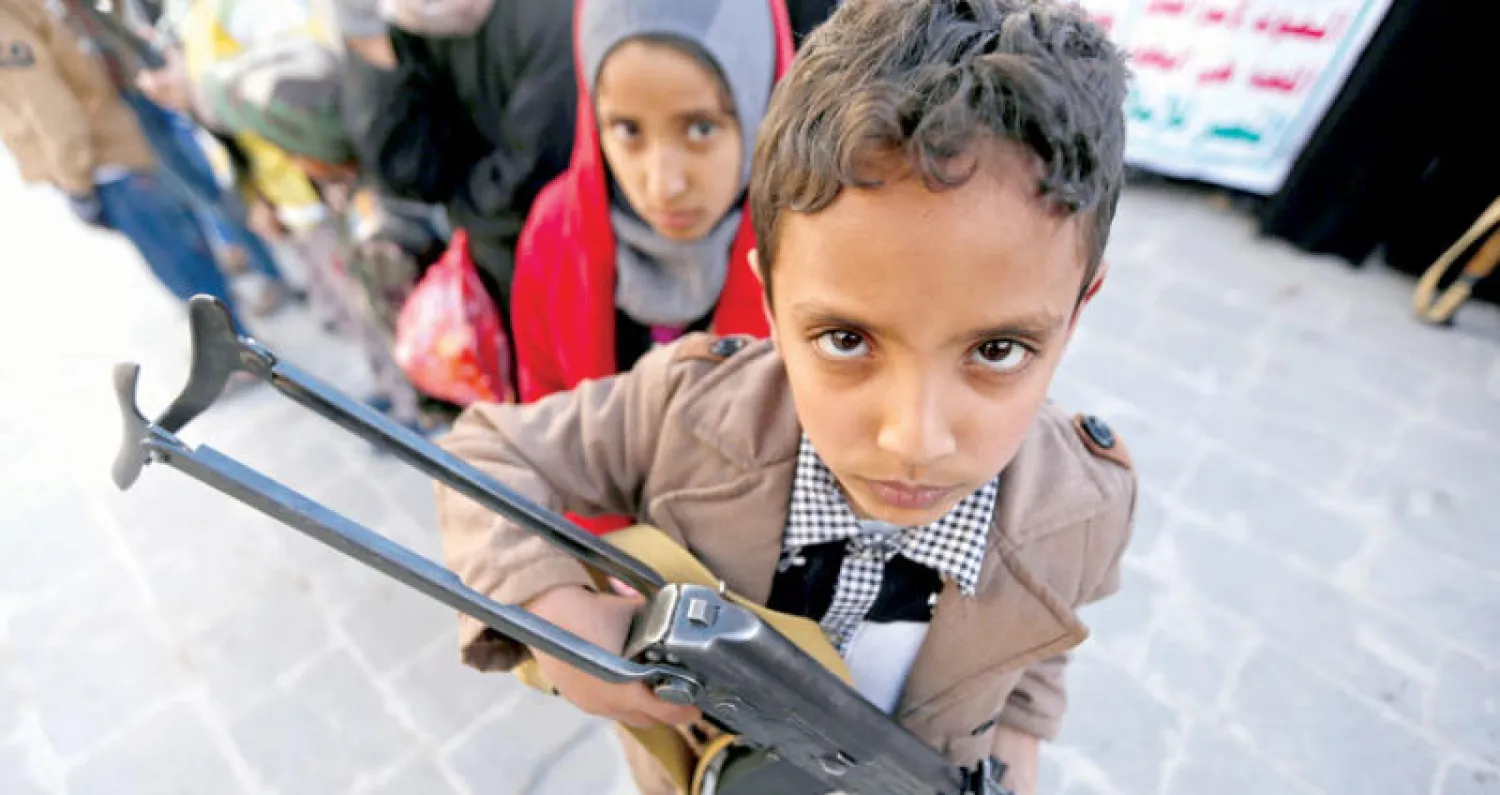 طفل يمني يحمل سلاحا في تجمع حوثي بصنعاء (رويترز)