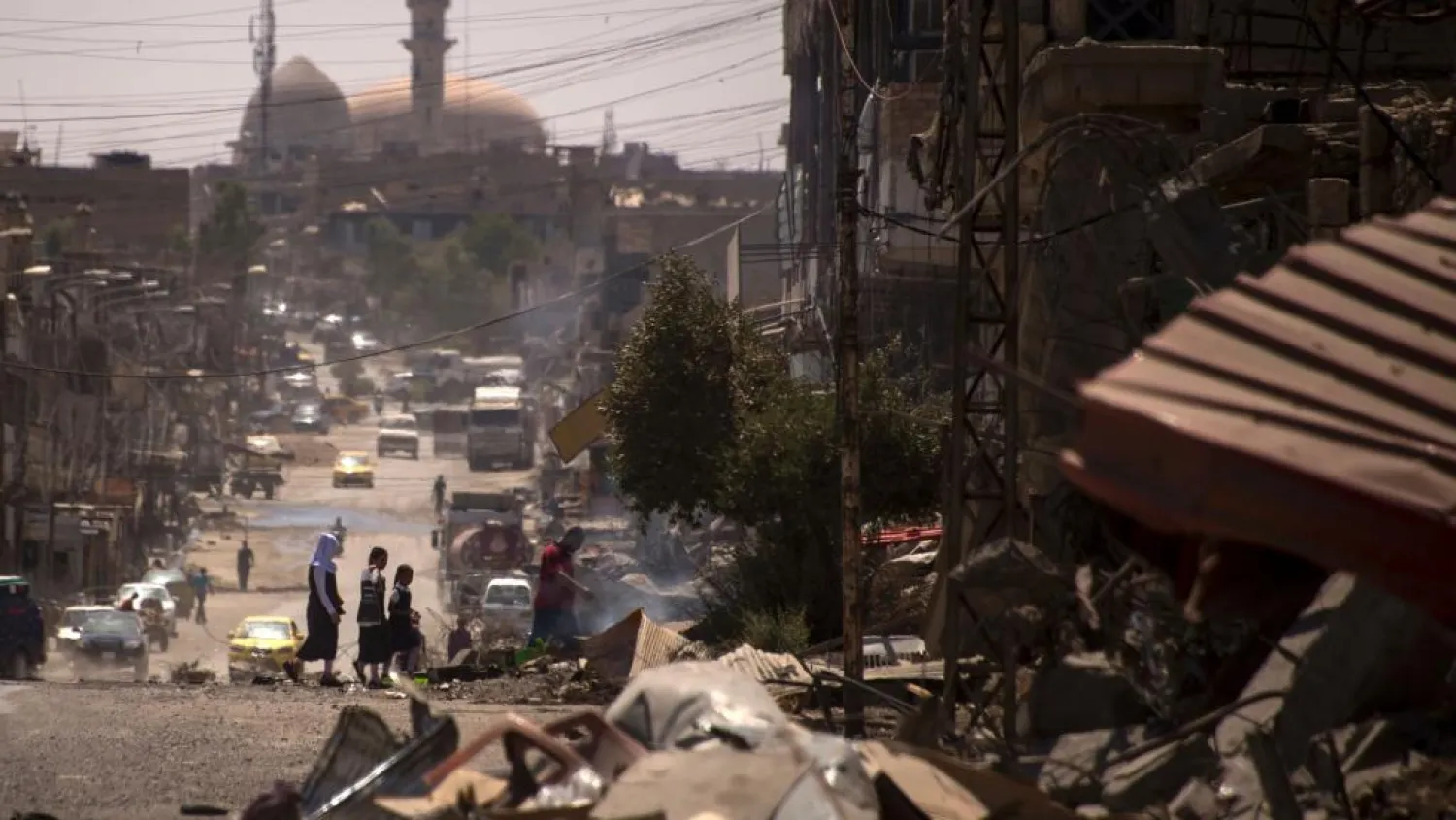 Iraqis walk on a damaged street in west Mosul. AFP file photo