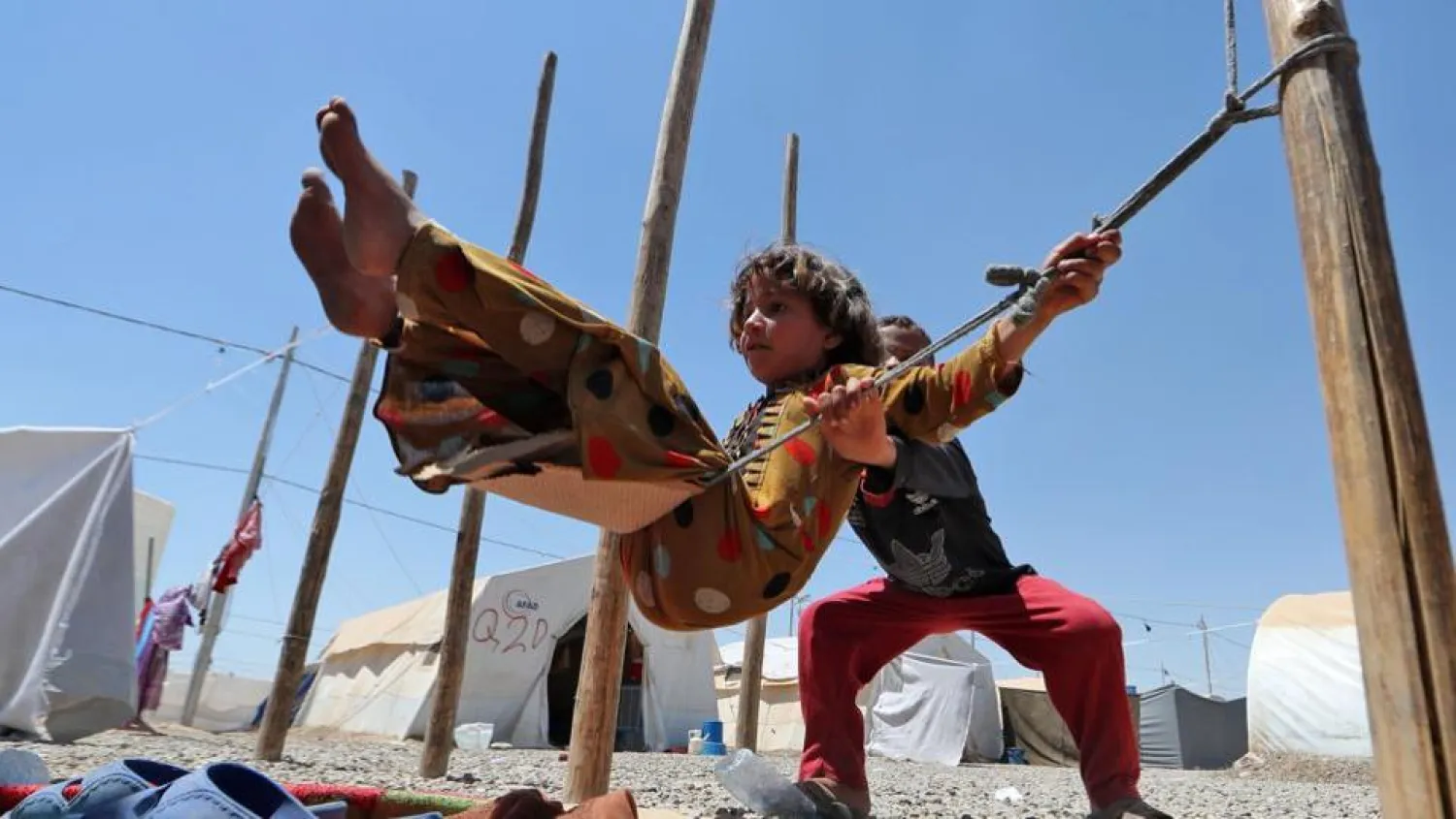 Displaced Iraqi children play on a makeshift swing at al-Khazir camp for the internally displaced, located between Erbil and Mosul. AFP file photo