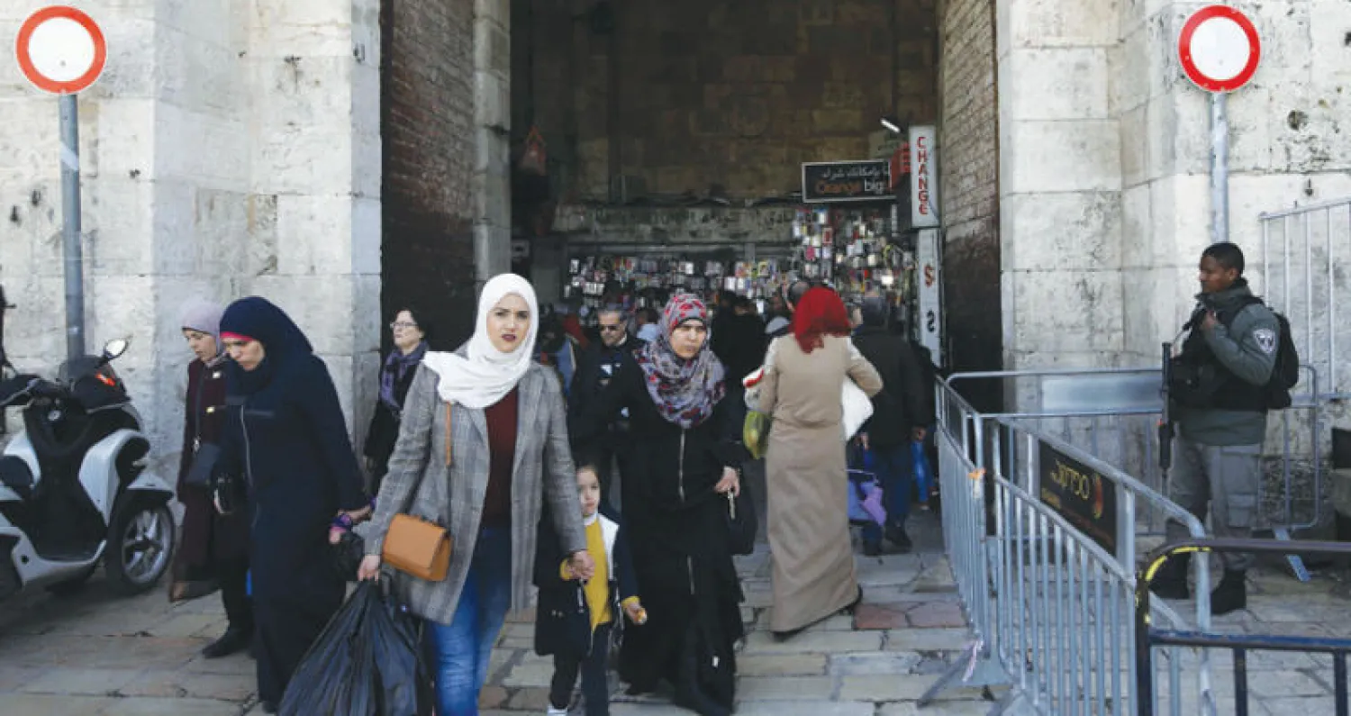 فلسطينيون يجتازون أحد حراس الحدود الإسرائيليين في القدس القديمة أمس (أ.ف.ب)