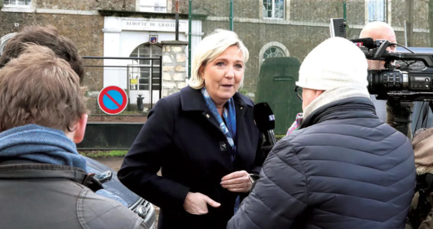 زعيمة اليمين المتطرف الفرنسي مارين لوبان تتحدث إلى مجموعة من الصحافيين خلال زيارتها إلى مركز إيواء المهاجرين خارج العاصمة باريس يوم الثلاثاء الماضي (أ.ف.ب)