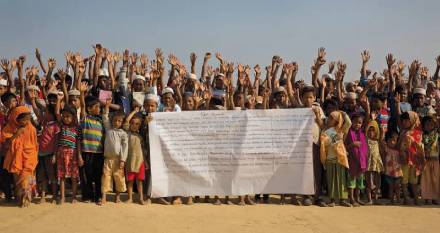 لاجئون من الروهينغا في مخيم بالونج كالي على الحدود بين ميانمار وبنغلاديش يرفعون عريضة بمطالبهم للعودة إلى ميانمار  (أ.ب)