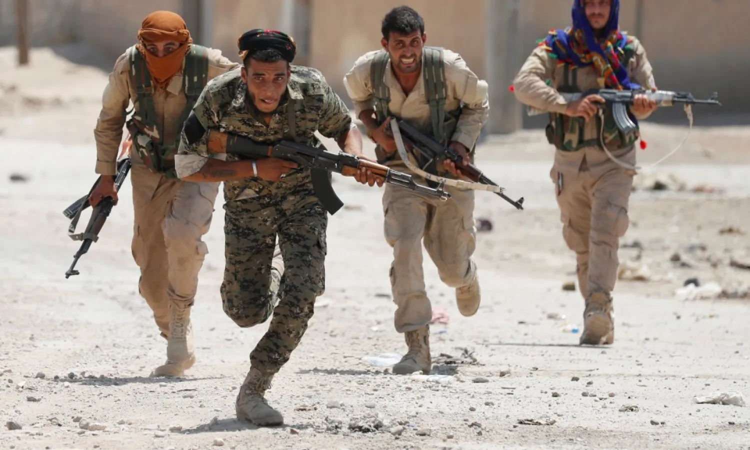 Kurdish fighters from the YPG run across a street in Raqqa, Syria July 3, 2017. Photo: Reuters / Goran Tomasevic