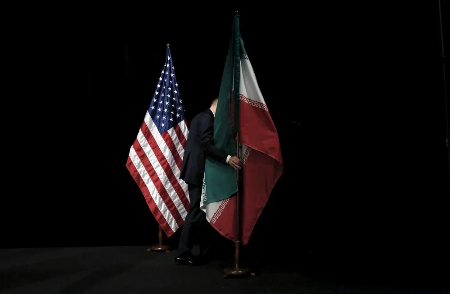 A staff member removes the Iranian flag from the stage after a group picture with officials during the Iran nuclear talks in Vienna, Austria in July 2015. (Reuters)