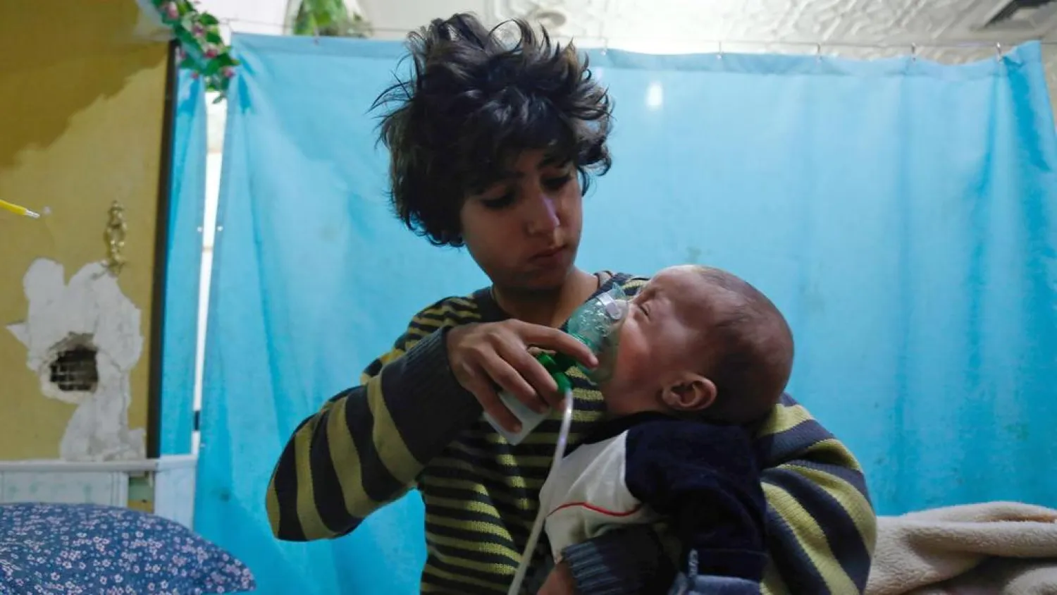 A Syrian boy holds an oxygen mask over the face of a baby at a makeshift hospital following a reported gas attack on the rebel-held besieged town of Douma in Eastern Ghouta on January 22, 2018. Hasan Mohamed / AFP