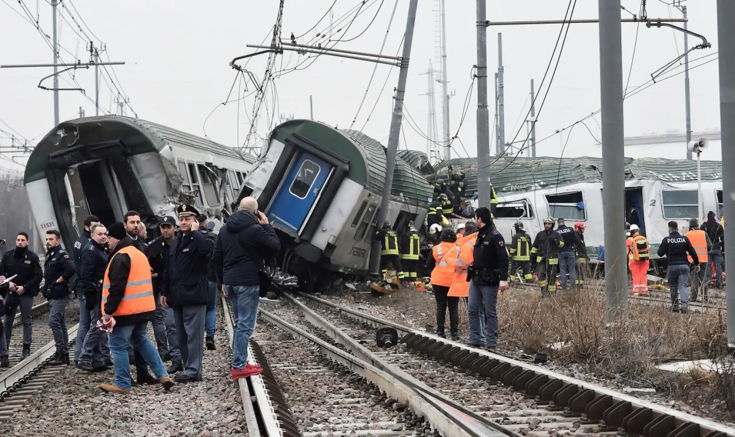Rescue workers and police officers stand near derailed trains in Pioltello, on the outskirts of Milan, Italy, January 25, 2018. REUTERS/Stringer