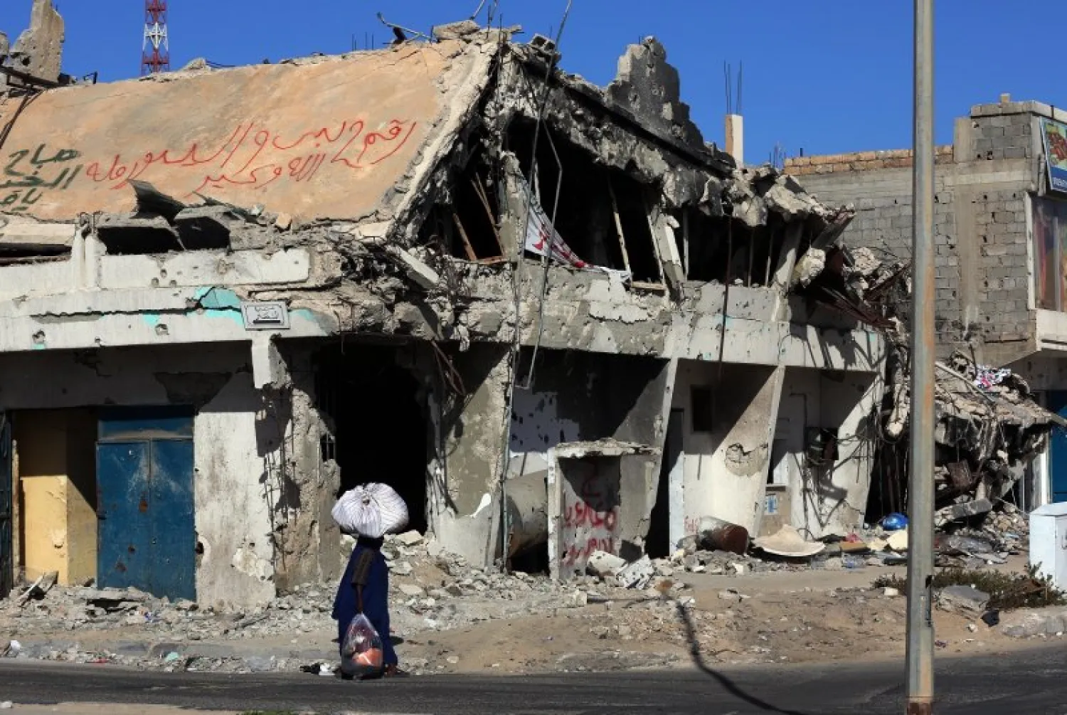 A Libyan woman walks past the rubble of a building in the Mediterranean city of Sirte. AFP file photo
