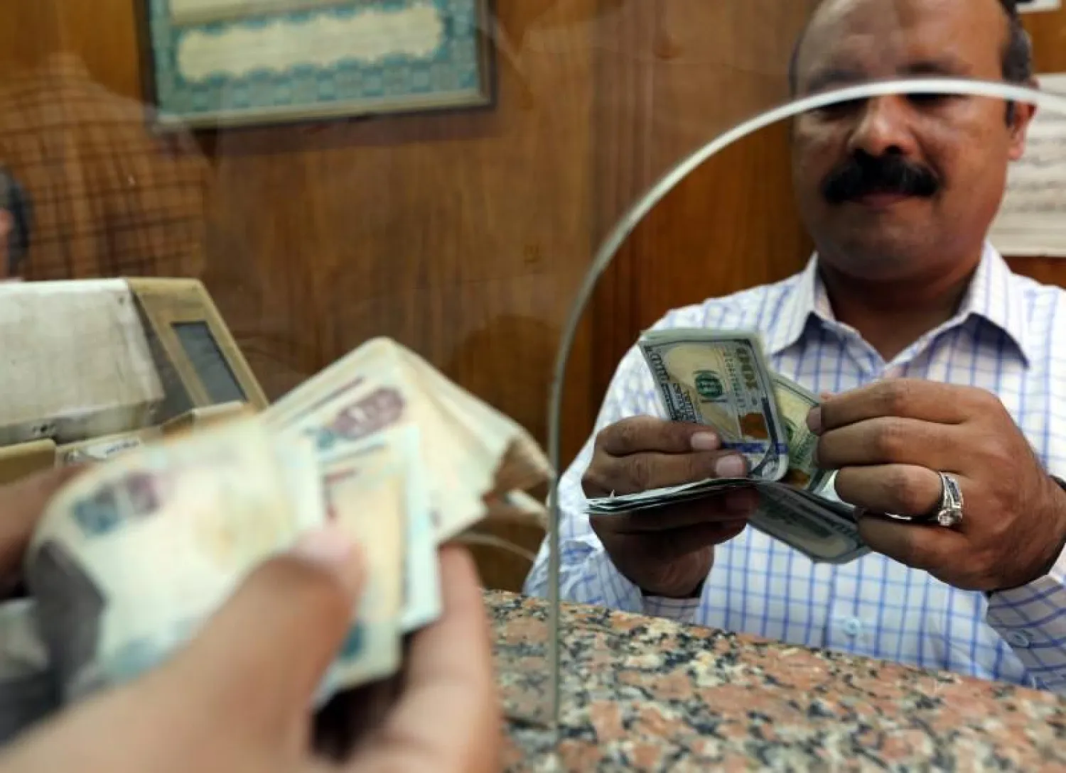 A customer counts US dollars in a bank in Cairo, Egypt, November 3, 2016. REUTERS/Mohamed Abd El Ghany