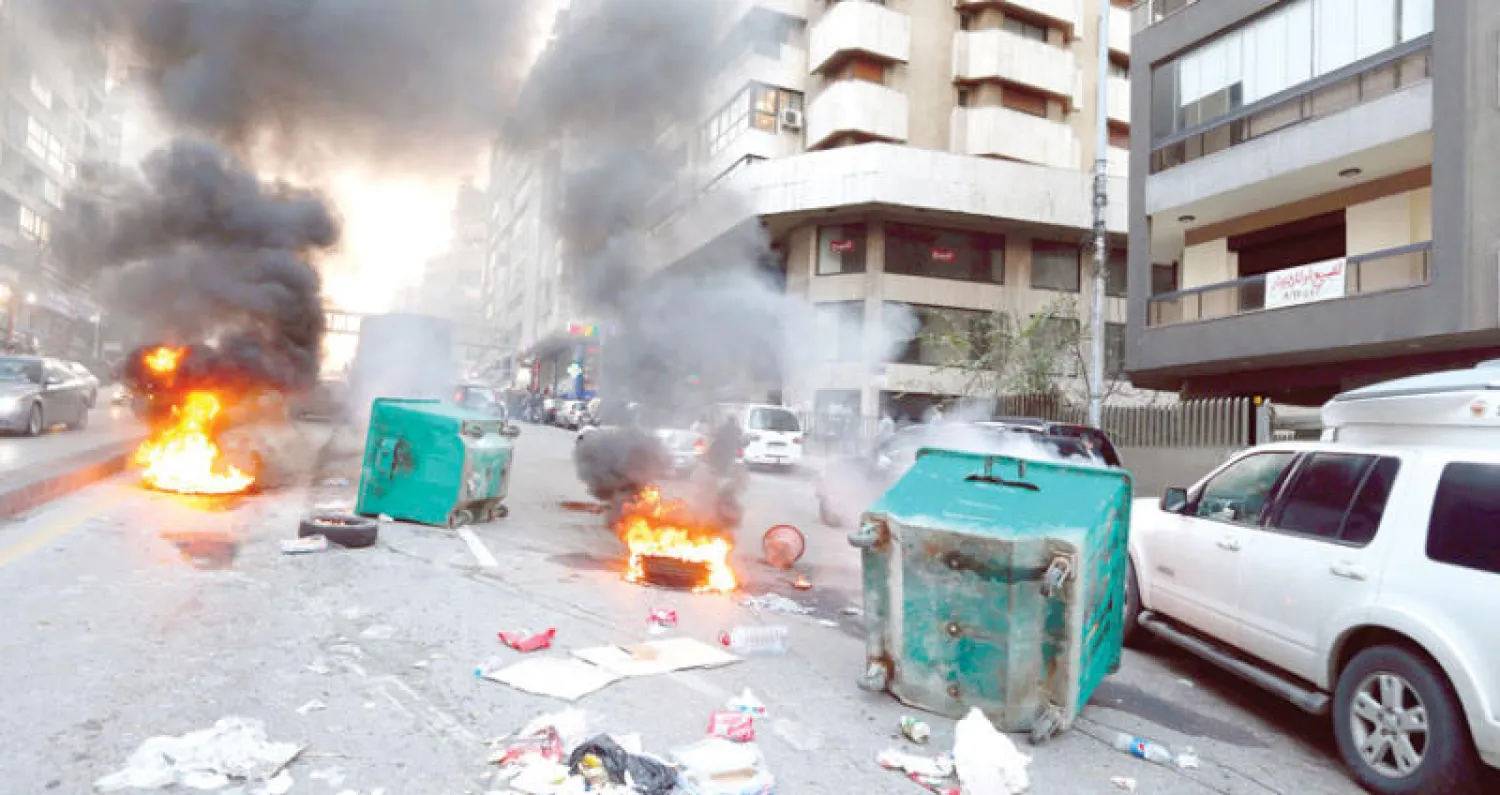 سيارات تجتاز الإطارات المحترقة في بيروت أول من أمس (رويترز)