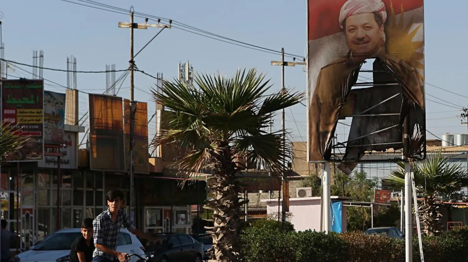 A burned poster of Massoud Barzani, the president of Iraq's autonomous Kurdish region, is displayed in front of the now abandoned building belonging to the Kurdish security forces in Kirkuk. Khalid Mohammed / AP
