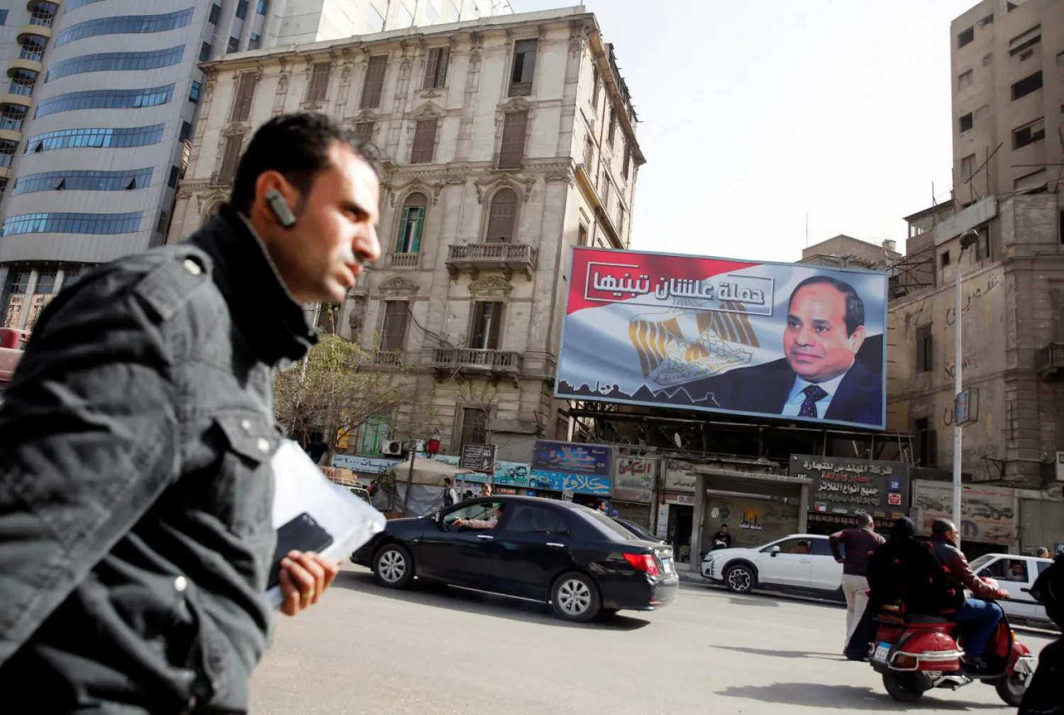 People walk by a poster of Egypt's President Abdel Fattah al-Sisi from the campaign titled “Alashan Tabneeha” (So You Can Build It) for the upcoming presidential election in Cairo, Egypt, January 22, 2018. Picture taken January 22, 2018. REUTERS/Amr Abdallah Dalsh
