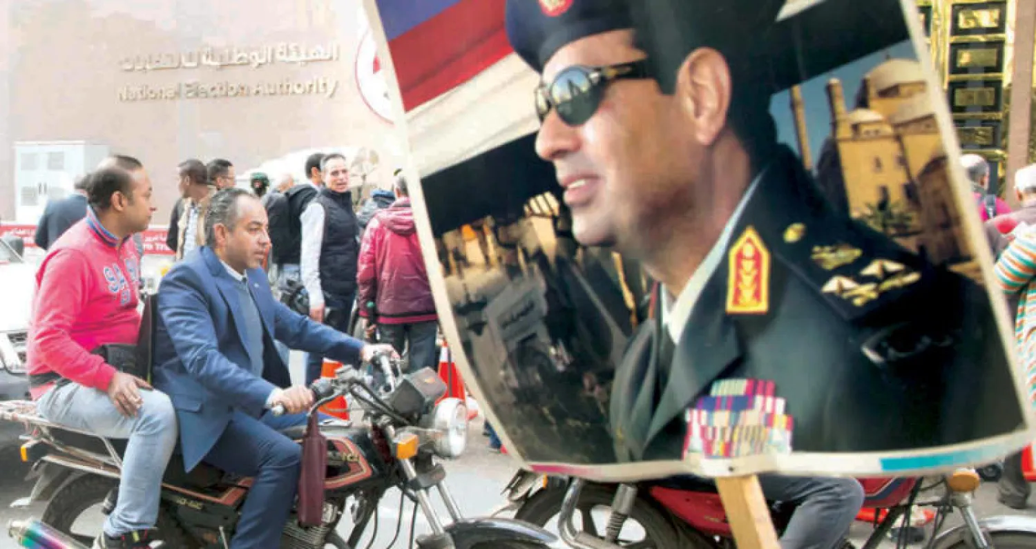 مصري يرفع صورة الرئيس المصري عبد الفتاح السيسي أمام مقر الهيئة الوطنية للانتخابات وسط القاهرة أمس (أ.ب)