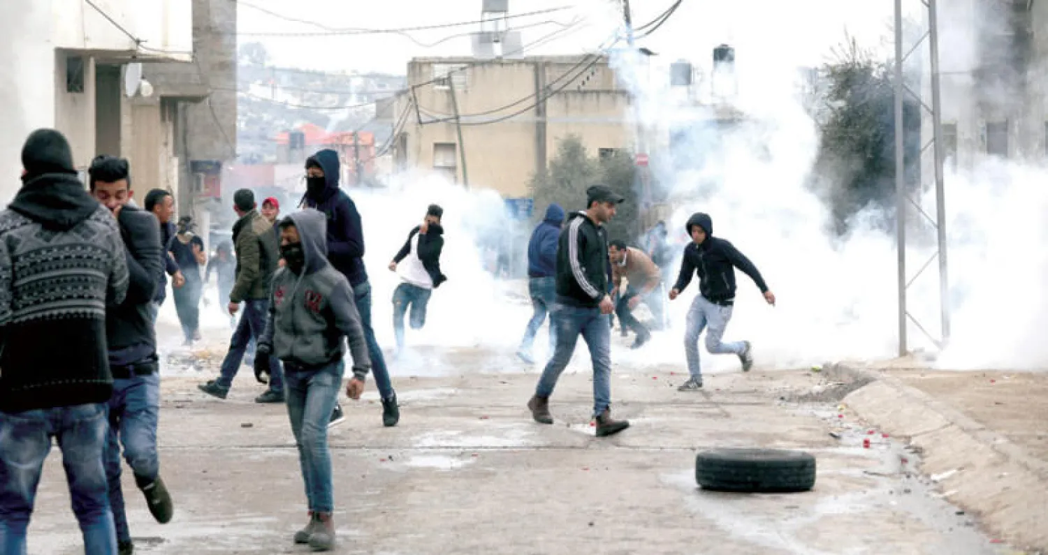 فلسطينيون يرمون قوات الاحتلال الإسرائيلي بالحجارة في قرية يامون قرب جنين بالضفة الغربية (إ.ب.أ)