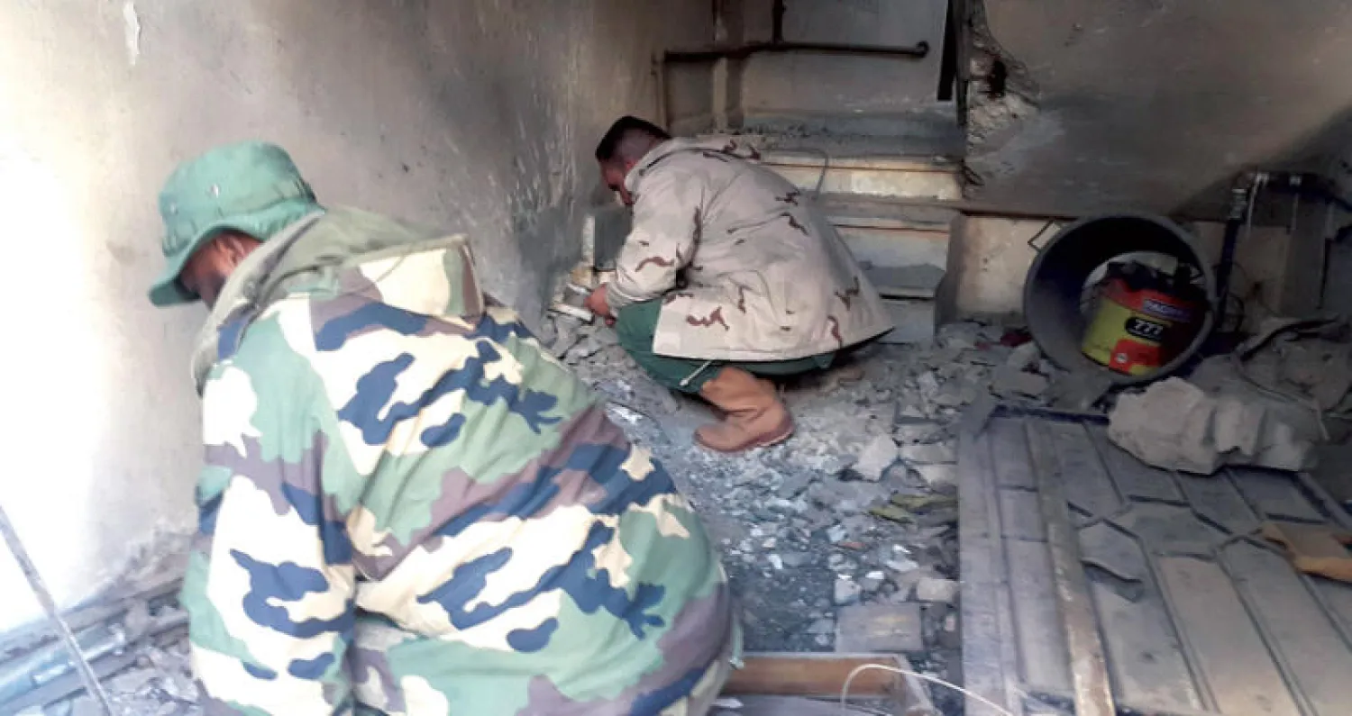 عنصران من الجيش الوطني الليبي خلال عمليات البحث عن ألغام تركها متطرفون في مدينة بنغازي (رويترز)