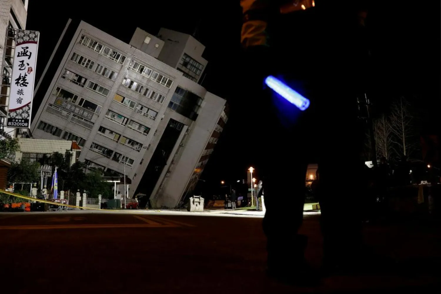 A police officer stands guard outside a damaged building after an earthquake hit Hualien, Taiwan February 7, 2018. REUTERS/Tyrone Siu