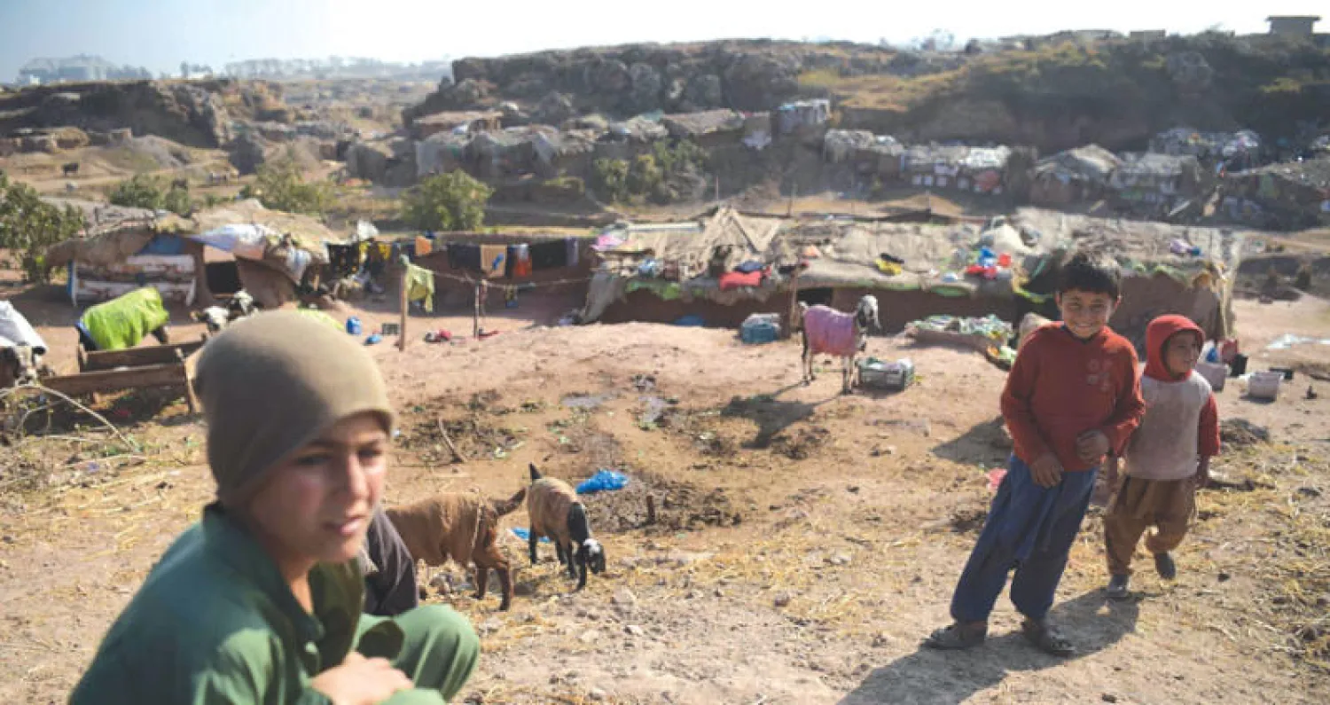 أطفال أفغان خارج منزلهم في مخيم عشوائي على تخوم إسلام آباد حيث يعيش عشرات آلاف الأفغان في منازل من طين وسط فقر مدقع دون مياه وكهرباء (أ.ف.ب)