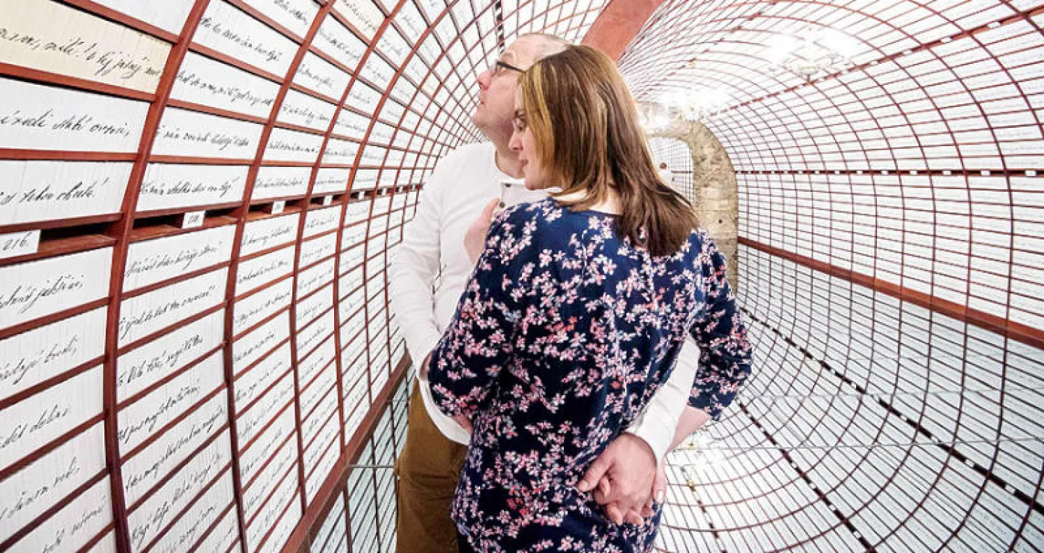 زوجان ينظران لقصيدة الحب داخل بنك الحب وهو جزء من المعرض التفاعلي المخصص لأطول قصيدة حب في العالم (أ.ف.ب)