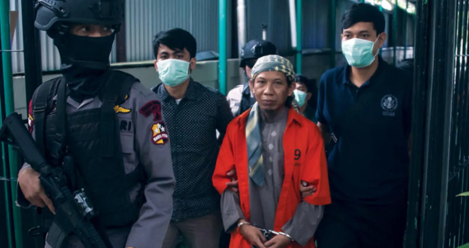 أمان عبد الرحمن مؤسس جماعة «أنصار الدولة» المرتبطة بتنظيم «داعش» حضر إلى قاعة محكمة جنوب جاكارتا وسط حراسة أمنية مشددة أمس (أ.ف.ب)