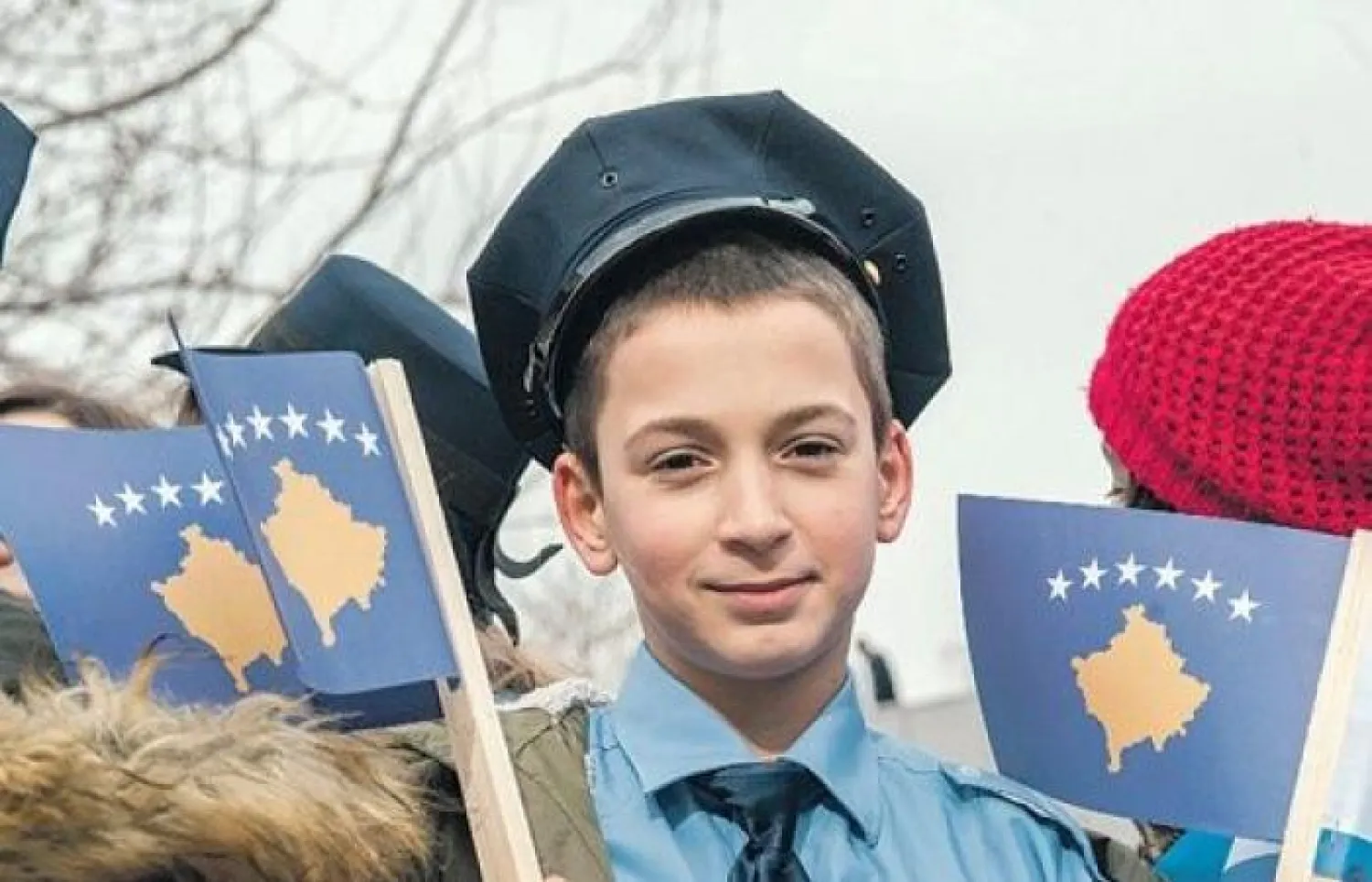 فتى كوسوفي يرتدي ملابس الشرطة ويرفع علم بلده في 16 فبراير 2018. (ا.ف.ب)