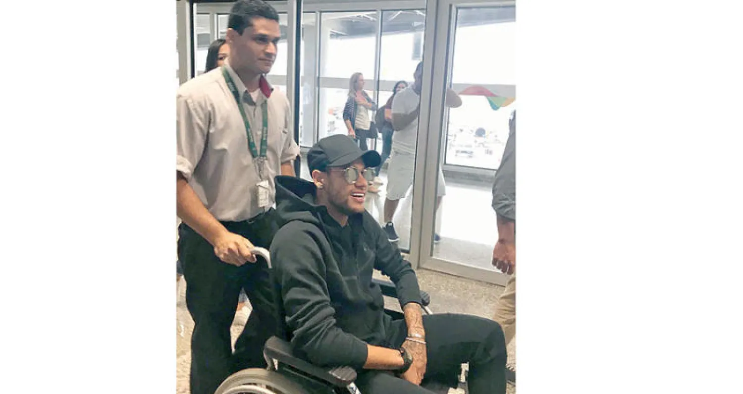 نيمار على كرسي متحرك لدى وصوله إلى البرازيل أمس (أ.ف.ب)