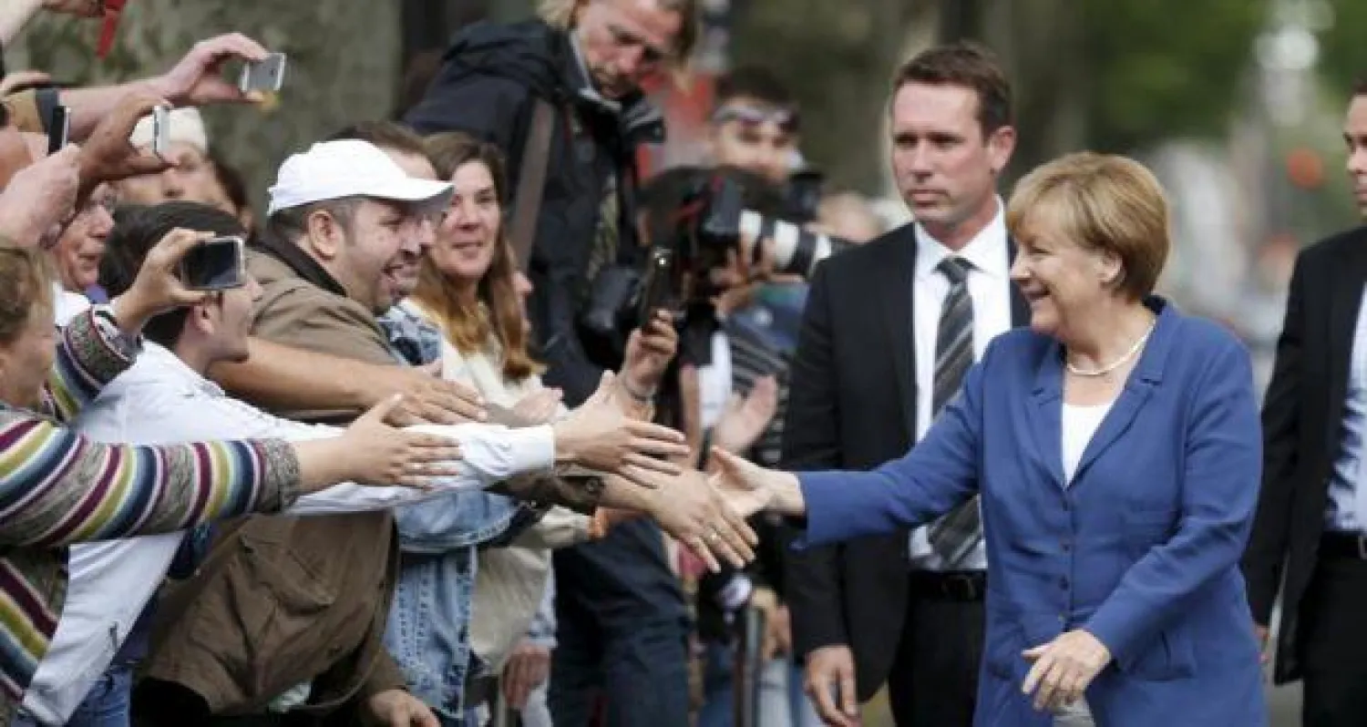 المستشارة الألمانية خلال تظاهرة رافضة للاعتداء على اللاجئين عام 2015. (رويترز)