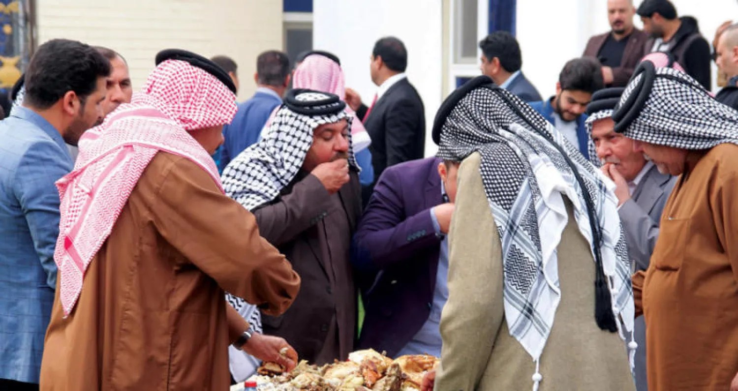 رجال عشائر يتناولون الطعام في مضيف بالرمادي مركز محافظة الأنبار (أ.ف.ب)