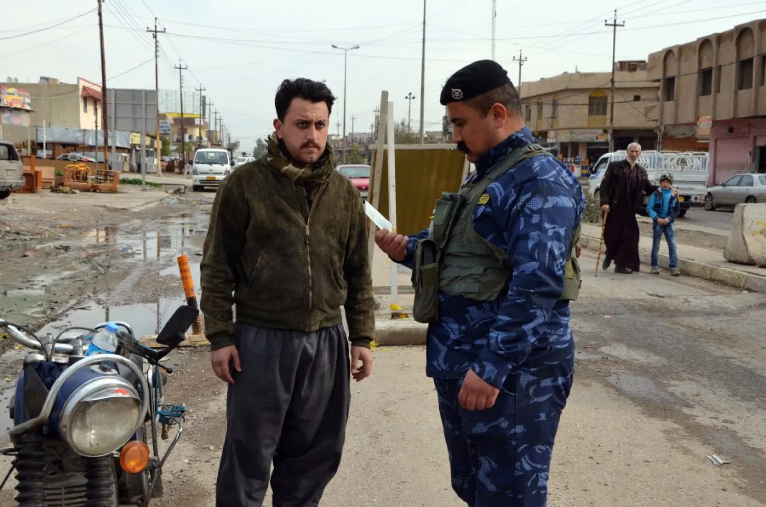 An Iraqi policeman checks the ID of a driver at a checkpoint in Mosul on February 22, 2018. (AFP)
