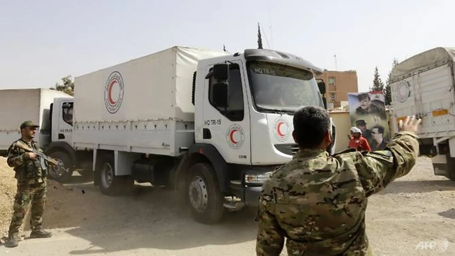 Syrian regime forces direct Syrian Arab Red Crescent trucks carrying aid at the al-Wafideen checkpoint on the outskirts of Damascus neighboring the rebel-held Eastern Ghouta region as they head towards the rebel-held enclave on Mar 5, 2018. AFP/Louai Beshara