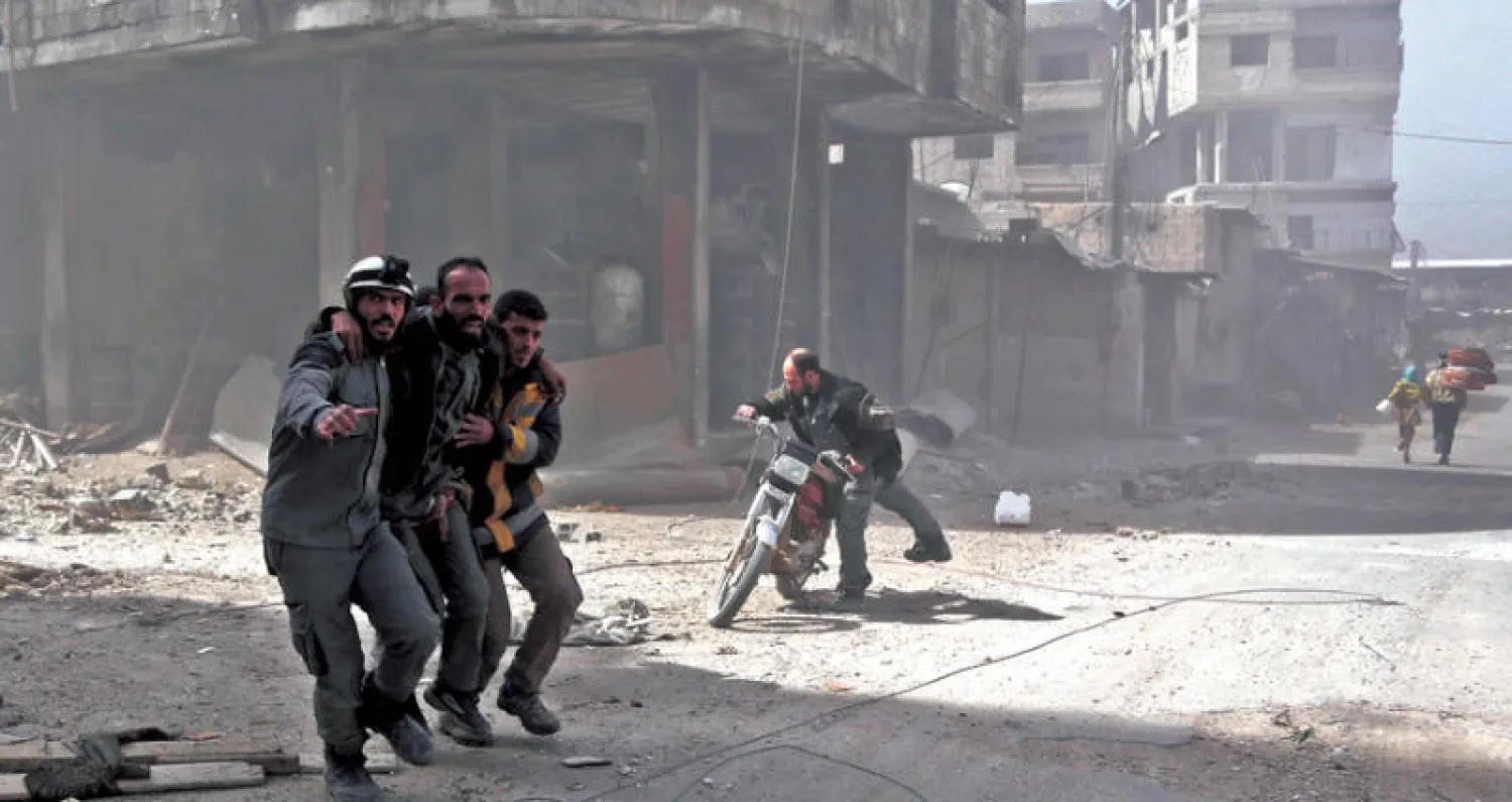 مساعدة جريح في غوطة دمشق أمس (أ.ف.ب)