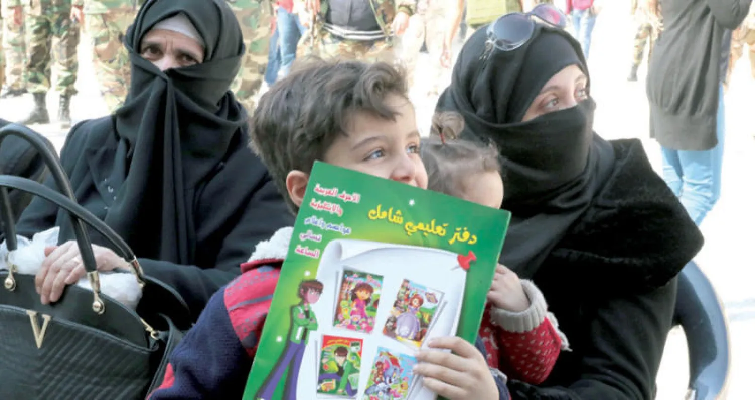 عائلة من الغوطة الشرقية تنتظر قرب الممر الآمن بانتظار الإجلاء أمس (إ.ب.أ)