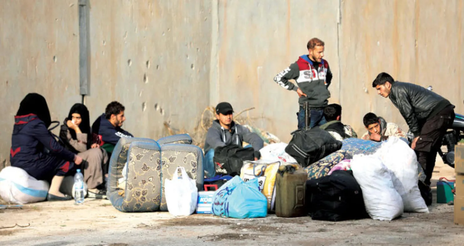 مقاتلو المعارضة وأسرهم الخارجون من حي القدم بريف دمشق لحظة وصولهم إلى قلعة المضيق بريف حماة أول من أمس (أ.ف.ب)