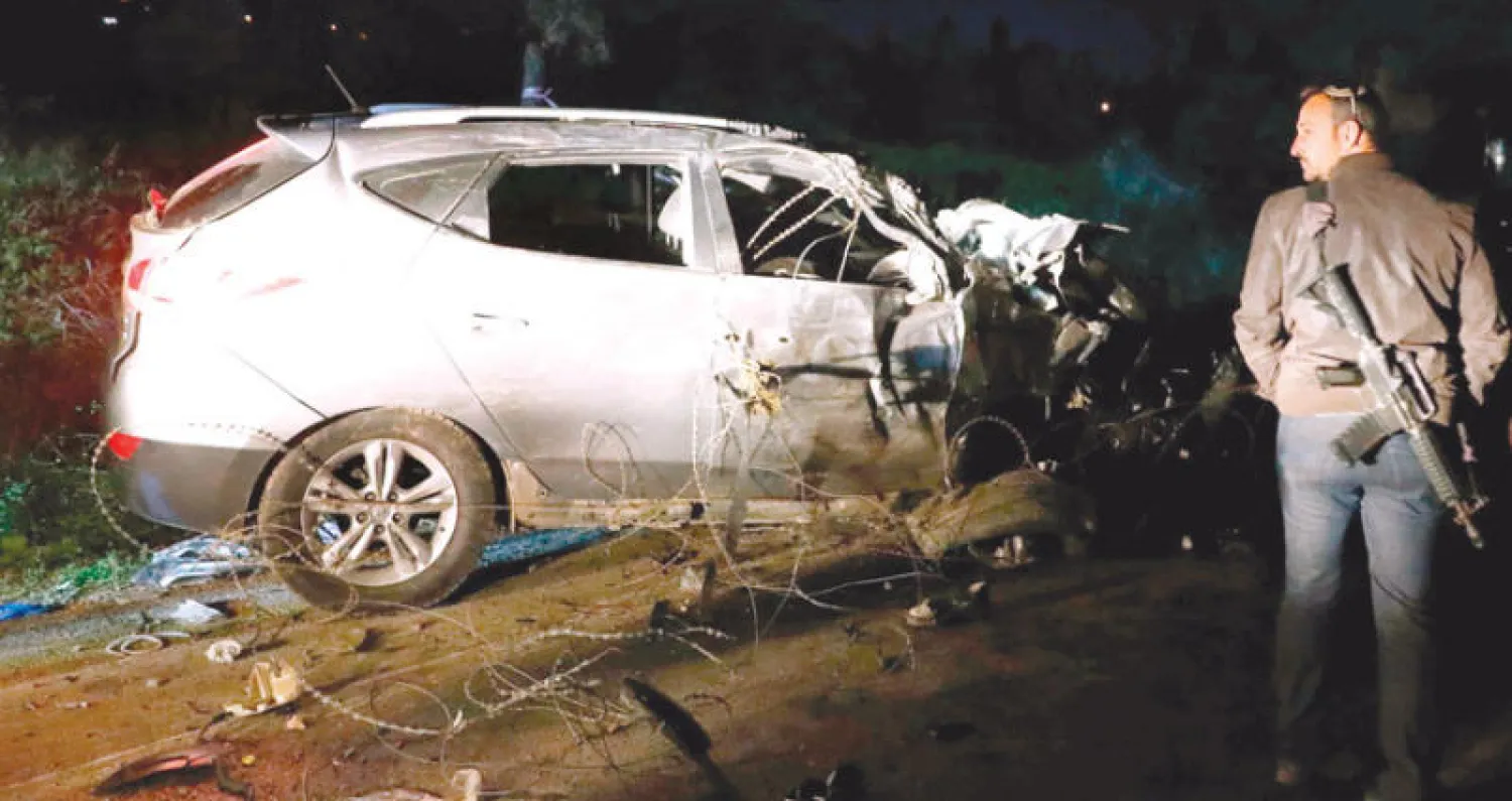 عنصر أمن إسرائيلي قرب السيارة المستخدمة في حادثة دهس الجنود شمال الضفة الغربية أمس (أ.ف.ب)