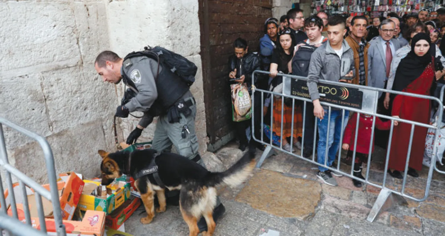فلسطينيون يتابعون شرطياً إسرائيلياً في موقع الهجوم المزعوم بالقدس (إ.ب.أ)