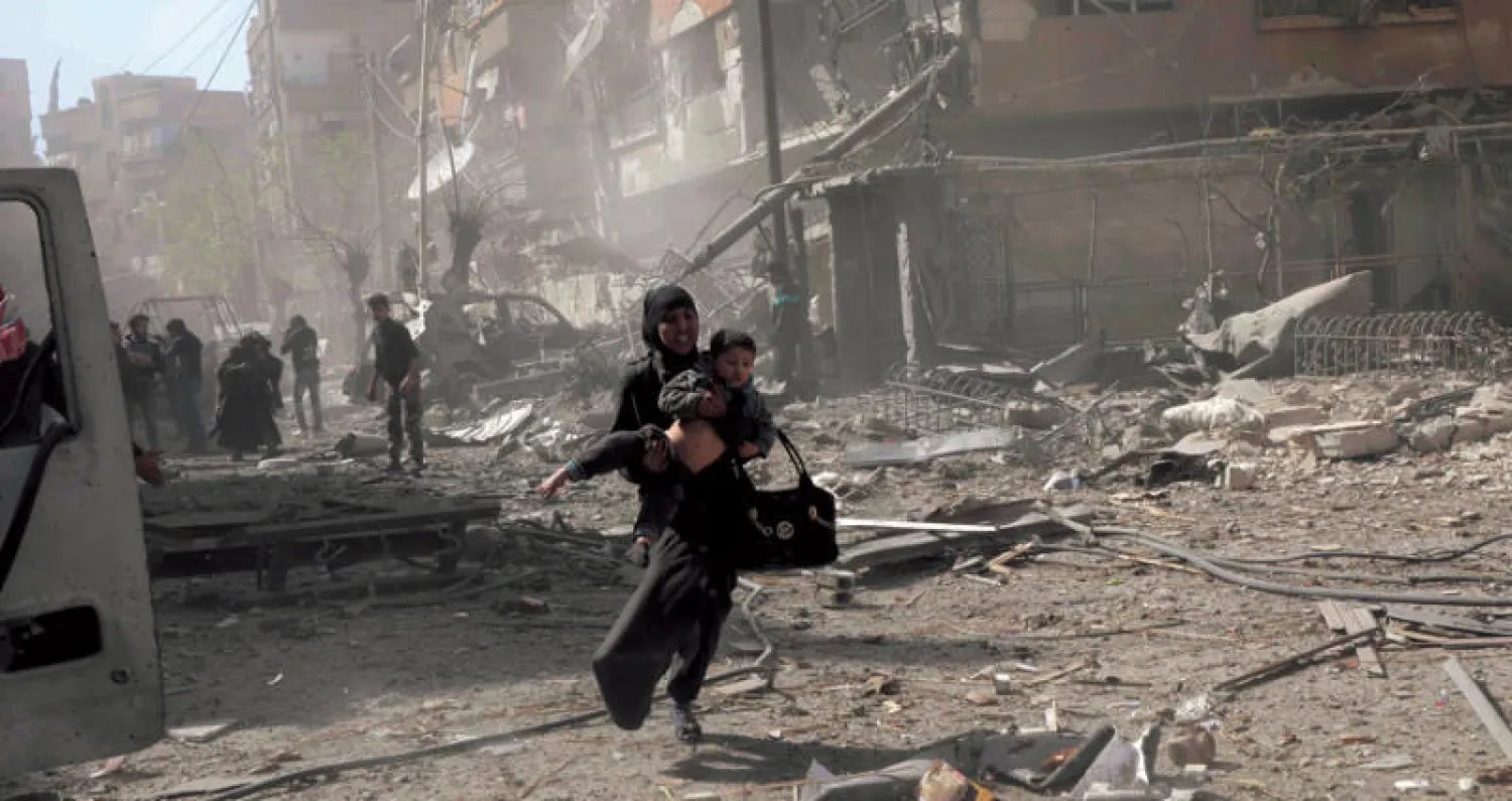 امرأة تحمل طفلها بعد غارة على دوما شرق دمشق أمس (أ.ف.ب)