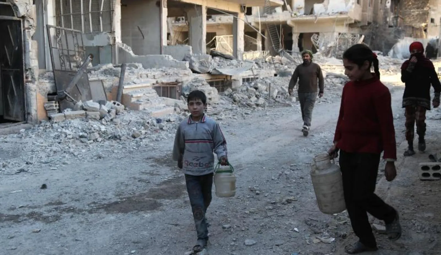 سوريون يحملون حاويات مياه لملء مضخة في جيب زملكا الذي تسيطر عليه المعارضة (أ.ف.ب)