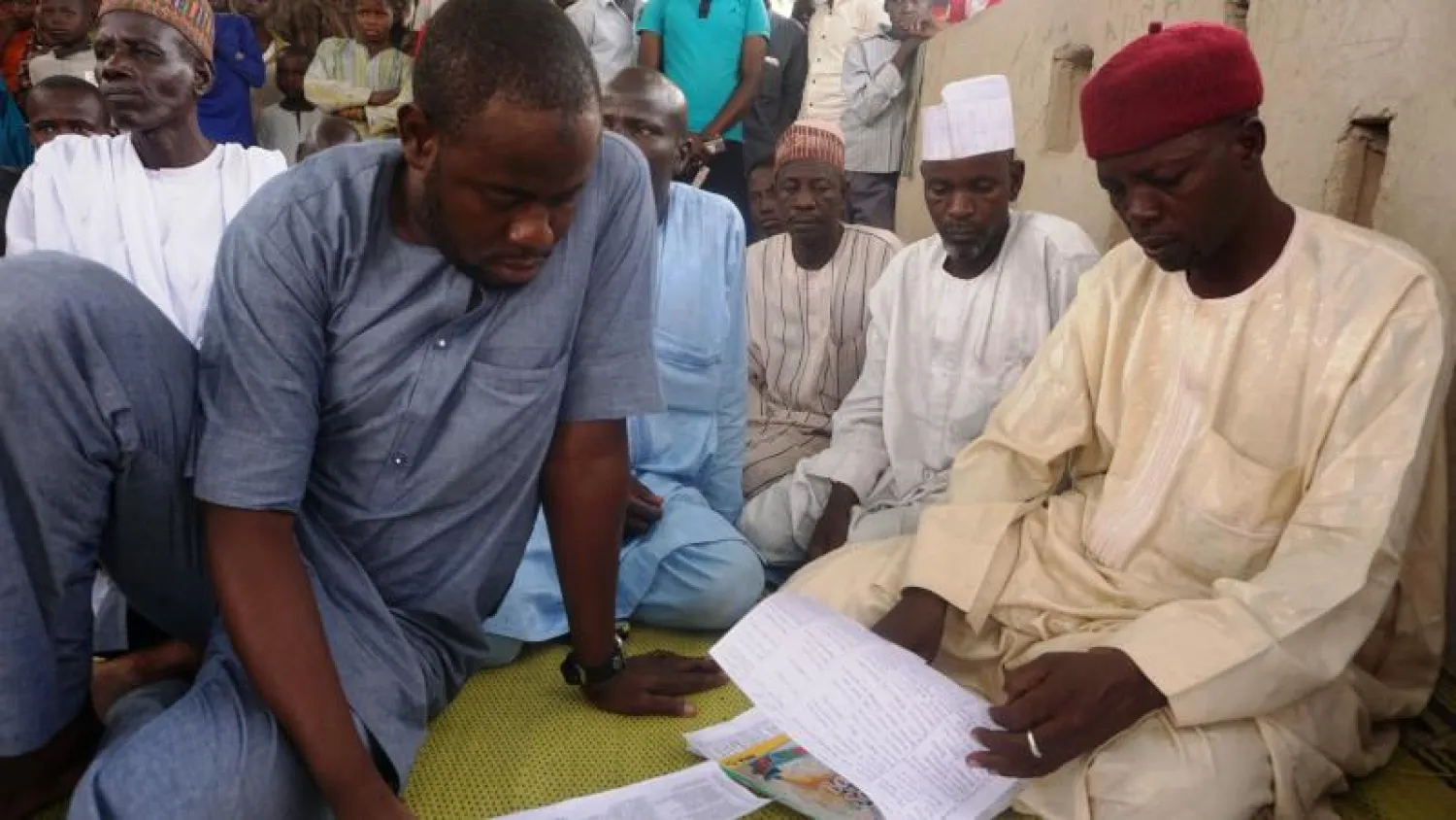 أولياء أمور يفحصون قائمة بأسماء 110 تلميذات اختطفتهن بوكو حرام من إحدى المدارس بمدينة دابتشي في شمال نيجيريا (أ.ف.ب)