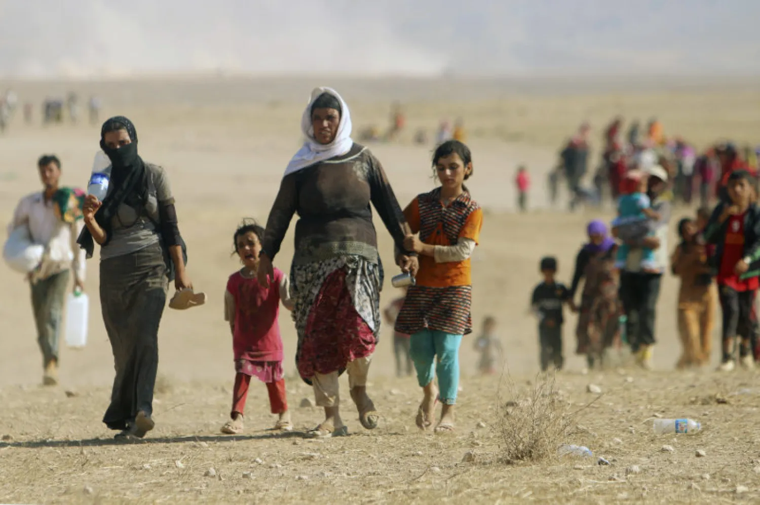Displaced people from the minority Yazidi sect, fleeing violence from forces loyal to ISIS in Sinjar town, walk toward the Syrian border, on the outskirts of Mount Sinjar, near the Syrian border town of Elierbeh of Al-Hasakah Governorate, August 11, 2014. REUTERS/Rodi Said