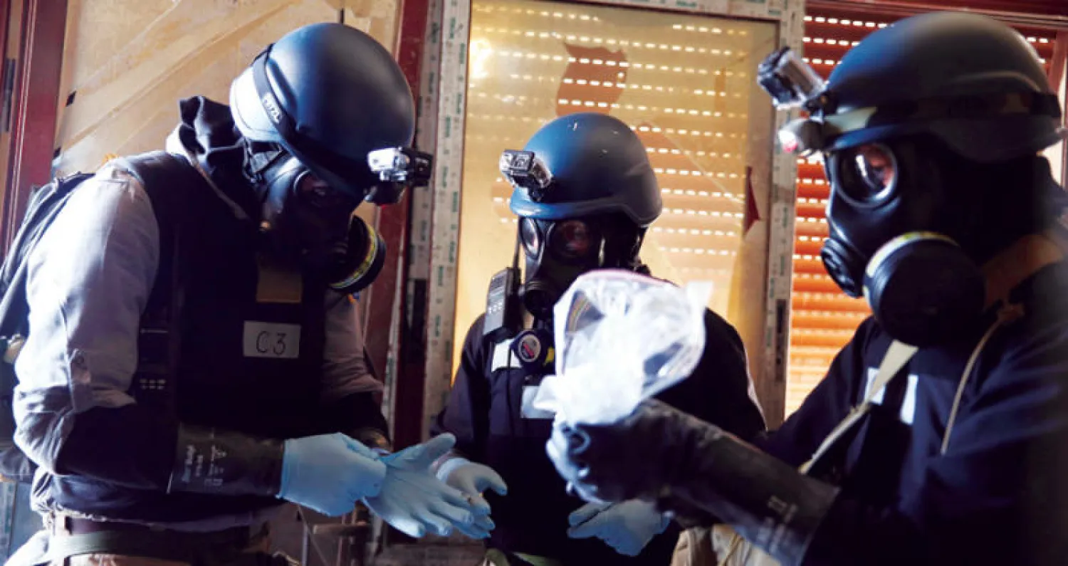 صورة من الأرشيف لخبراء من الأمم المتحدة يرتدون أقنعة واقية وينقلون عيّنات من موقع هجوم كيماوي مزعوم في عين ترما بغوطة دمشق في أغسطس 2013 (رويترز)