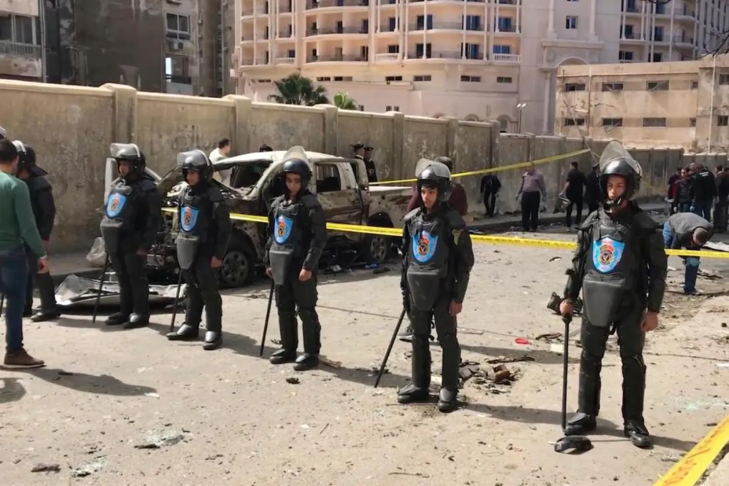 Security members stand guard as investigators search the area after a bomb placed under a nearby car exploded Saturday, March 24, 2018 in Alexandria, Egypt (AP Photo/Mohamed Khalil)