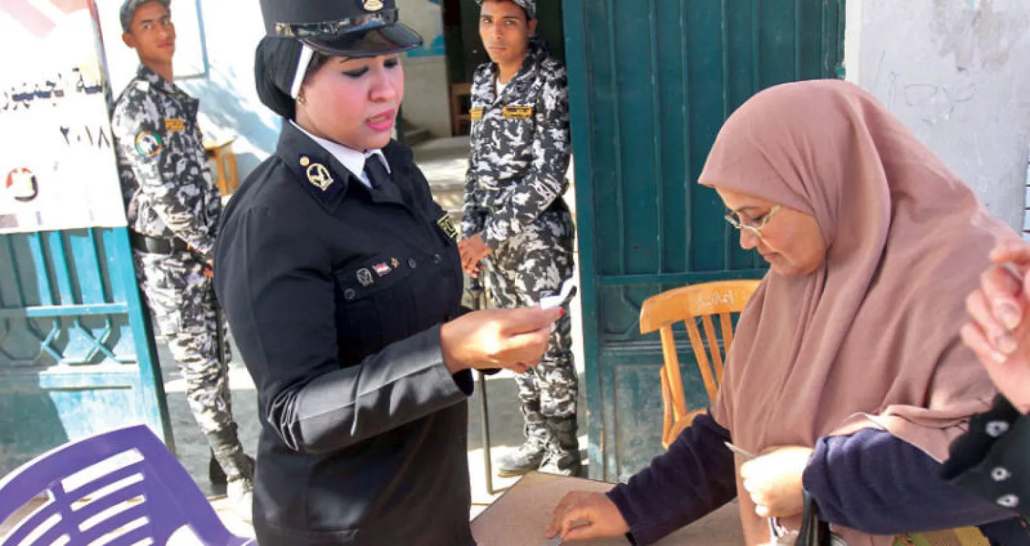 شرطية تدقق في هوية ناخبة في أحد مراكز التصويت في الإسكندرية أمس (أ.ف.ب)