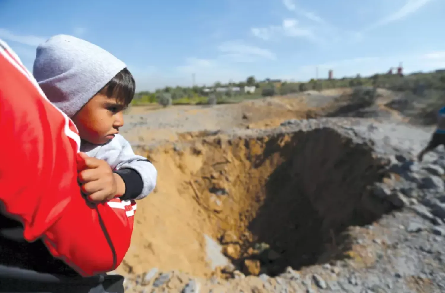  Palestinian boy is carried as he looks at the scene of an Israeli air strike, south of Gaza City, March 2018. Reuters
