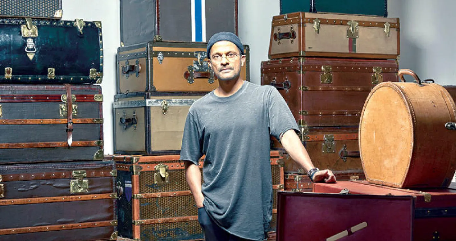 المصمم راميش نير أمام مجموعة من صناديق السفر القديمة