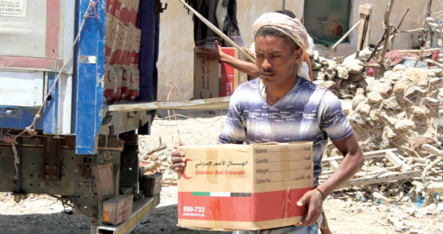 يمني يحمل مساعدات إنسانية وزعها «الهلال الأحمر الإماراتي» في الشريجة التابعة لمحافظة لحج الجنوبية أمس (أ.ف.ب)