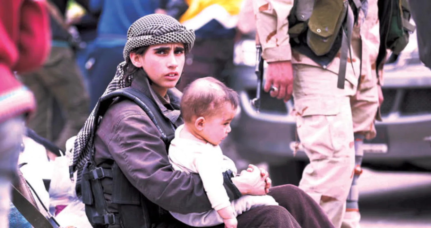 فتى يحمل رضيعاً بعد وصول المدنيين ومقاتلي المعارضة إلى ريف حماة إثر إجلائهم من الغوطة الشرقية أمس (أ.ف.ب)