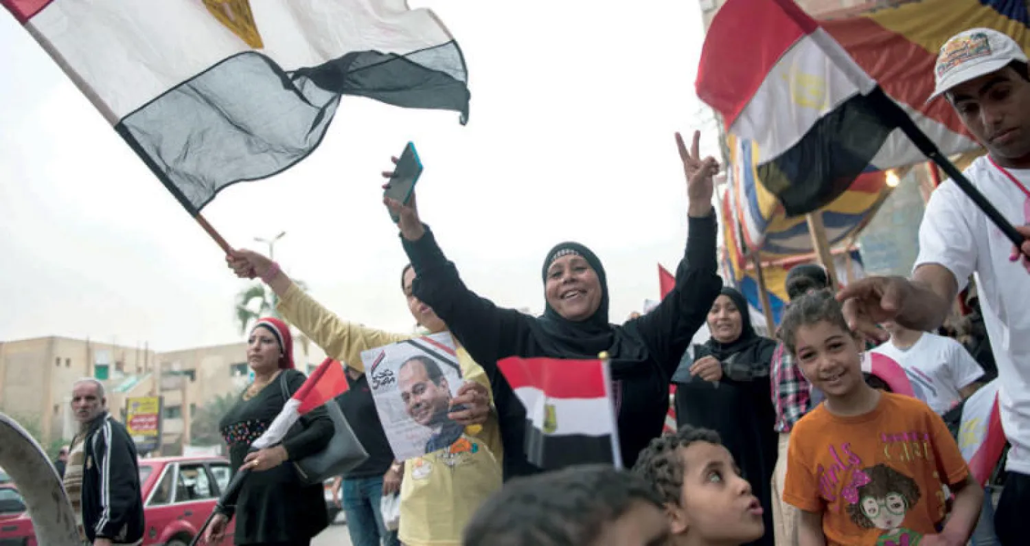 ناخبون يلوحون بأعلام أمام لجنة انتخابية في القاهرة أمس (إ.ب.أ)