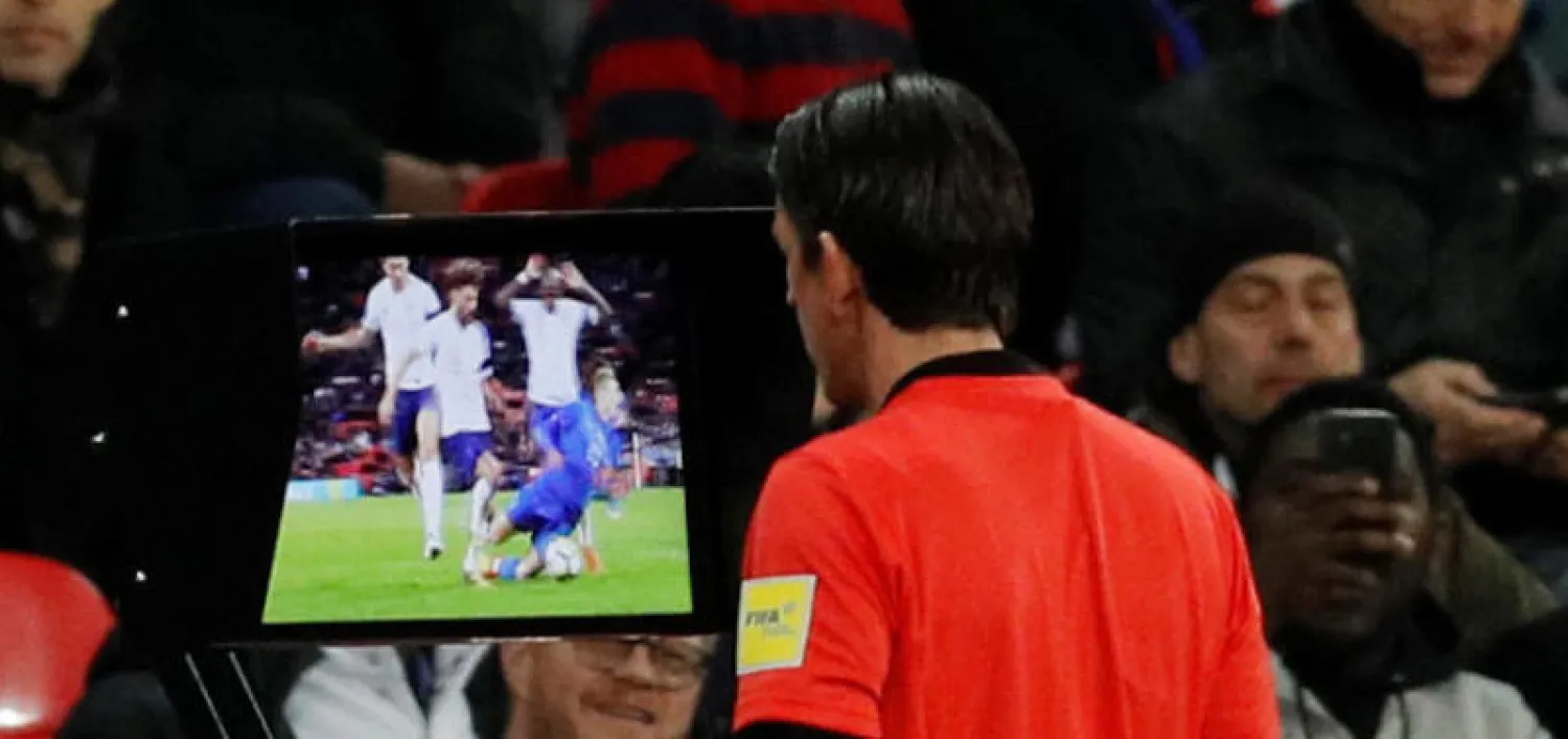 الحكم الألماني دينيز أيتكين يتحقق عبر تقنية حكم الفيديو المساعد إذا كانت إيطاليا تستحق ركلة جزاء في مواجهة إنجلترا الودية (أ.ف.ب)