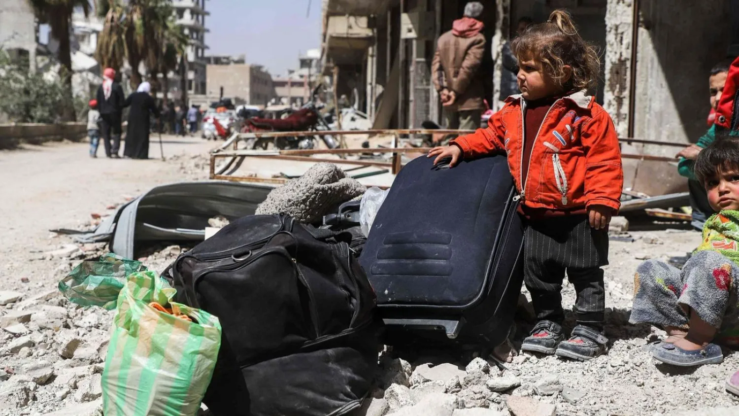 A Syrian child stands next to luggage with other civilians as they wait to be evacuated from the town of Arbin in the eastern Ghouta region on the outskirts of the capital Damascus. (AMER ALMOHIBANY / AFP)