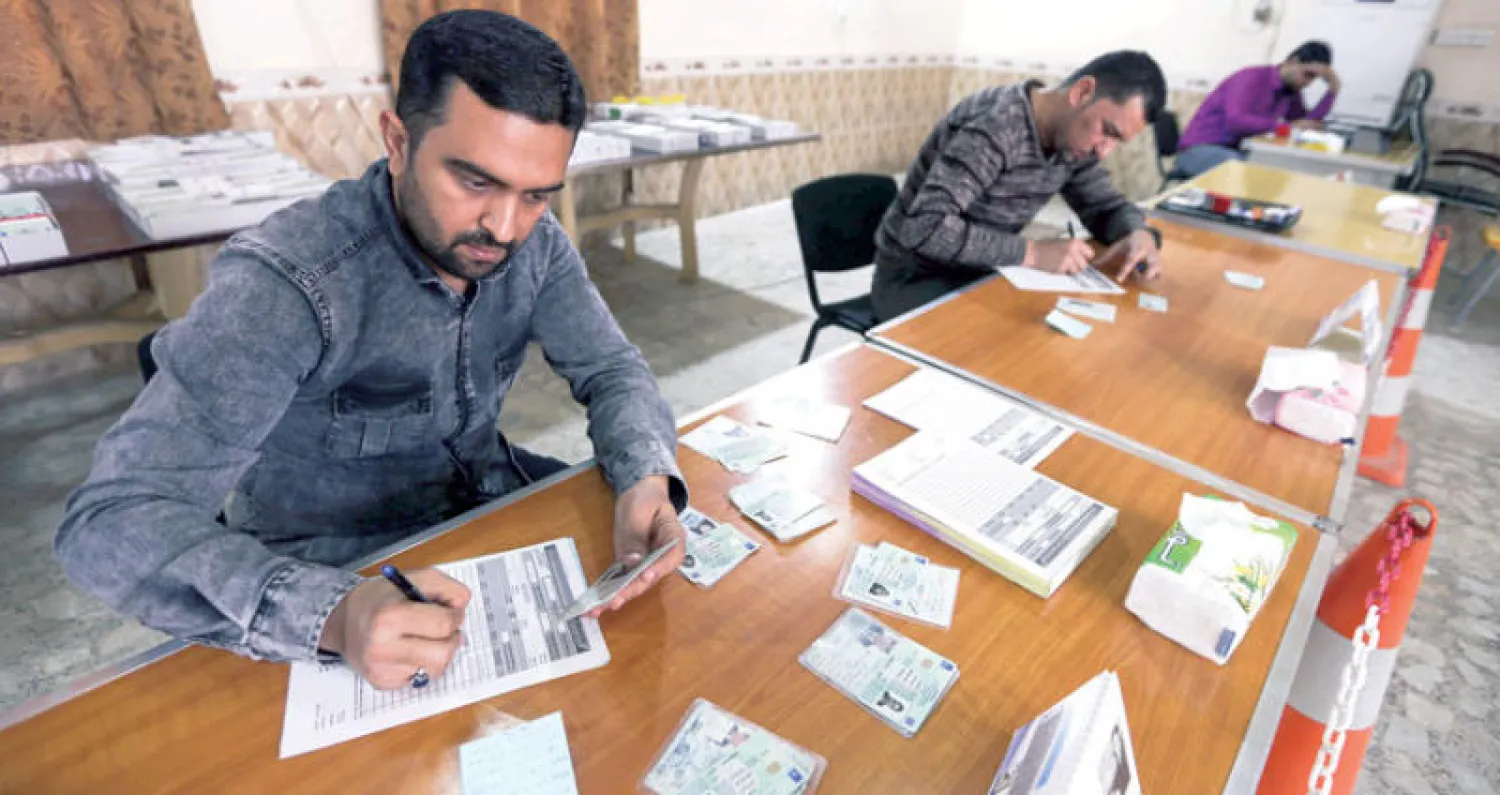 موظفون من المفوضية يجهزون بطاقات الناخبين في مدينة النجف (أ.ف.ب)